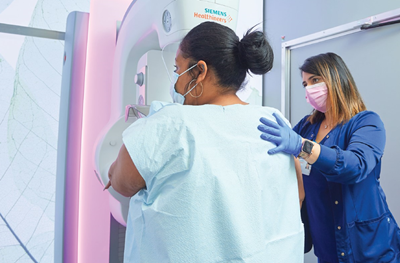 A woman receives a mammogram with a nurse standing next to her.